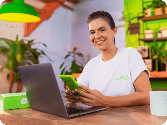 Mulher sorrindo, vestindo a camisa do programa de Consultores do Renda Extra Ton em frente a um mural xadrez com logotipos do Ton.