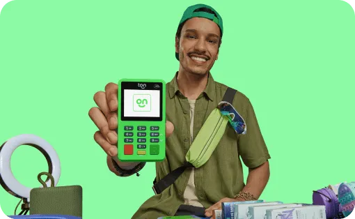 Empreendedor com um sorriso no rosto, mostrando o visor de sua maquininha verde com a logo do Ton,