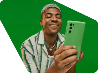 Empreendedor em um fundo verde sorrindo e olhando para o seu celular com uma capinha verde.