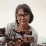 Empreendedora Maria Lígia sorrindo e mostrando seus produtos
