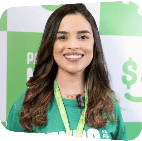Consultora sorrindo. Mulher vestindo a camisa e crachá do programa de afiliados de Renda Extra Ton em frente a um mural xadrez com as logos do Ton.