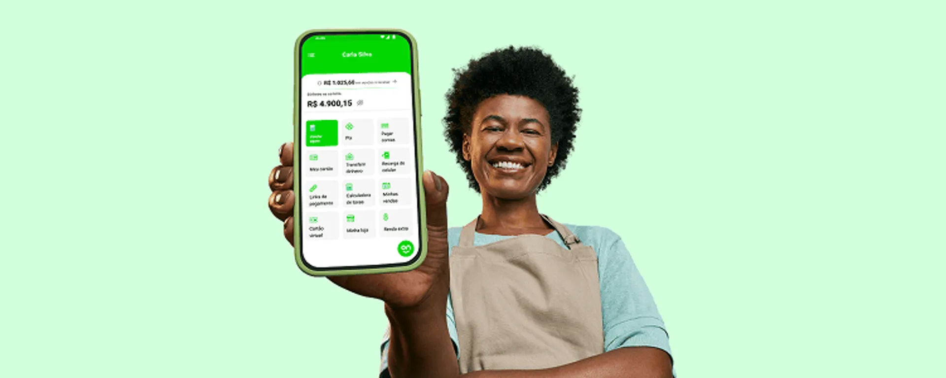 Empreendedora sorrindo, com um braço cruzado e o outro segurando o seu celular na sua frente com o aplicativo do Ton aberto na página inicial. E no celular constam os serviços do Ton e o saldo de sua conta.